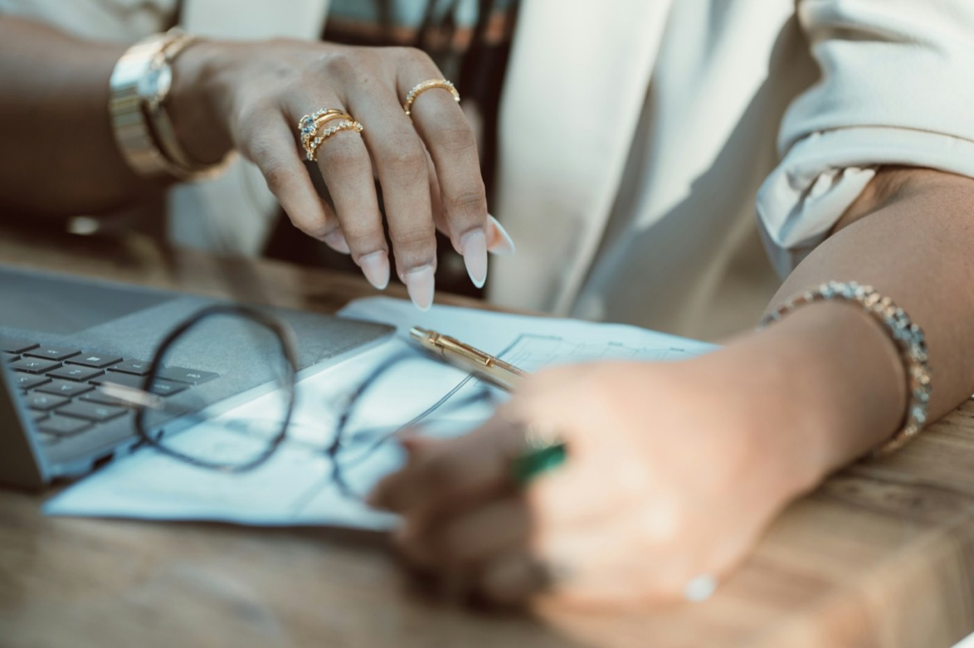 A designer’s hands over a sheet of drawings with a pair of glasses