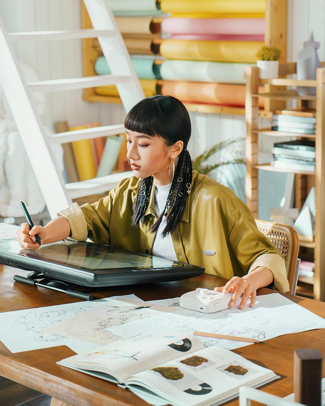 A designer drawing on a tablet at a desk scattered with color samples