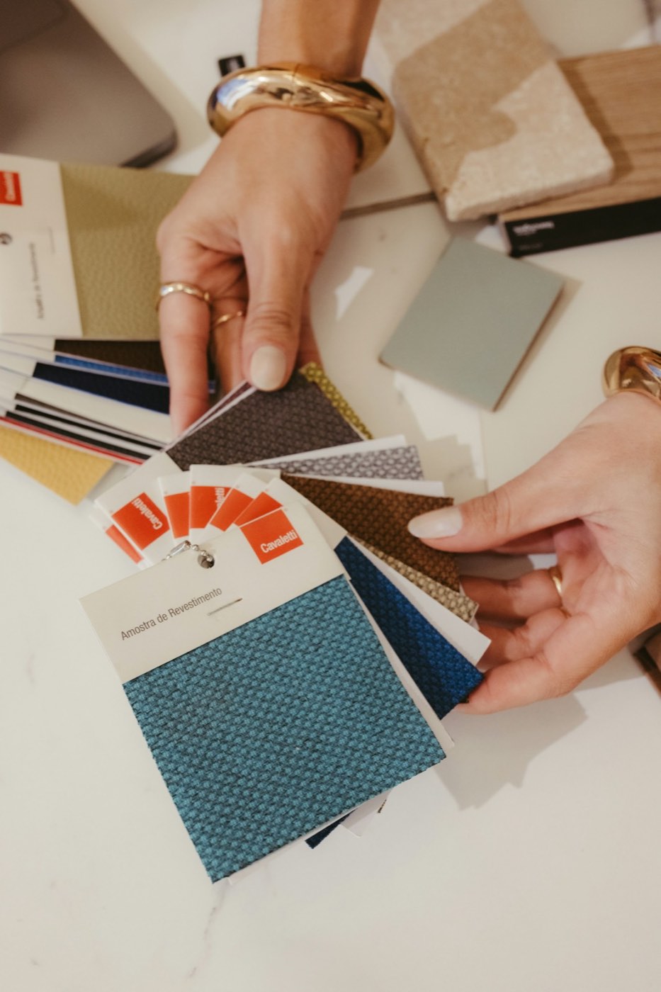 A hand fanning out fabric and paint samples in warm colors